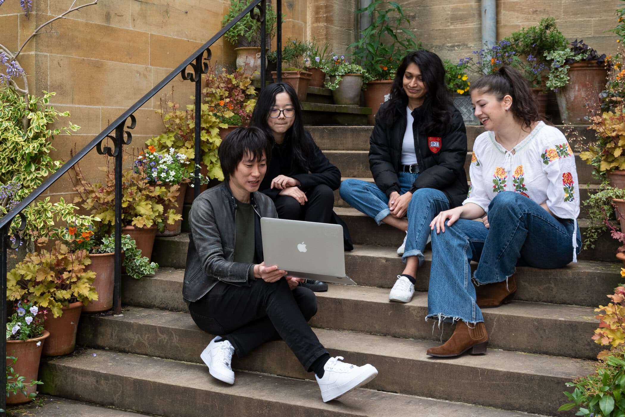 Students huddled around a laptop on the steps of the Principal's Lodgings.