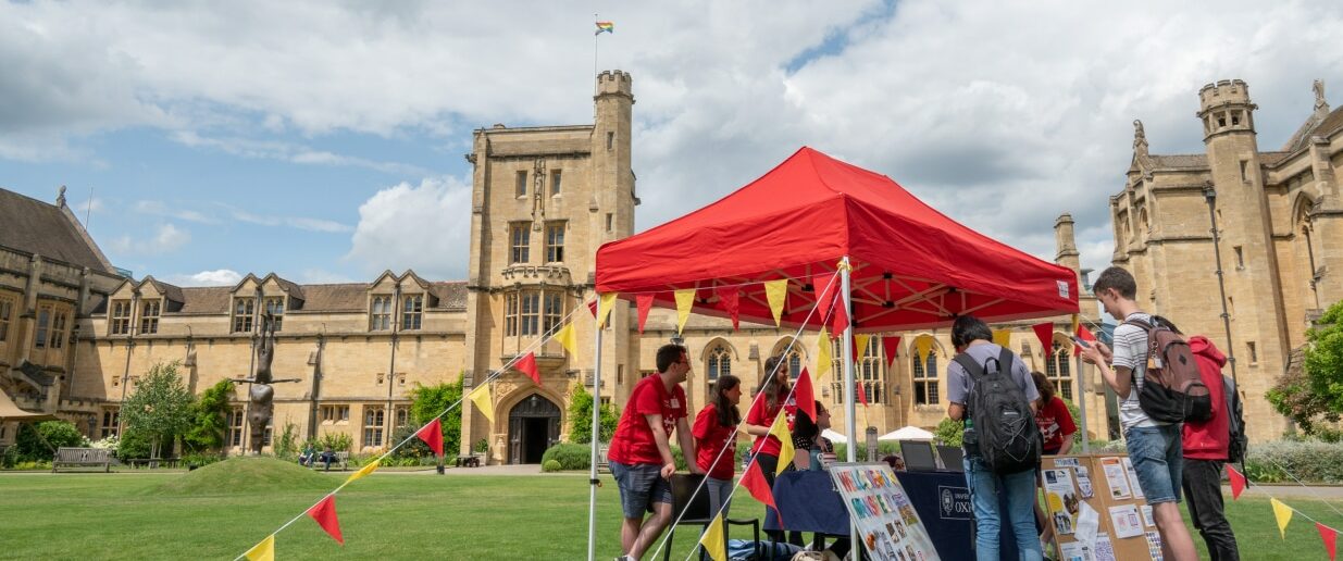 Red pop up gazebo with red and yellow buntings and students and visits around it