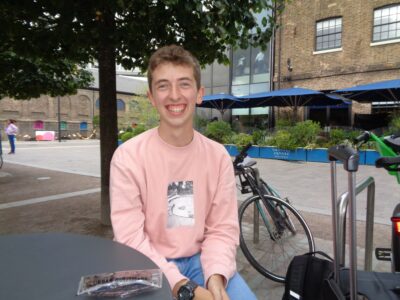 Photo of Alex sat outside with a tree and bike in the background