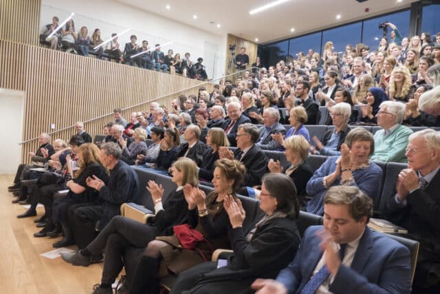 Audience members auditorium clapping.