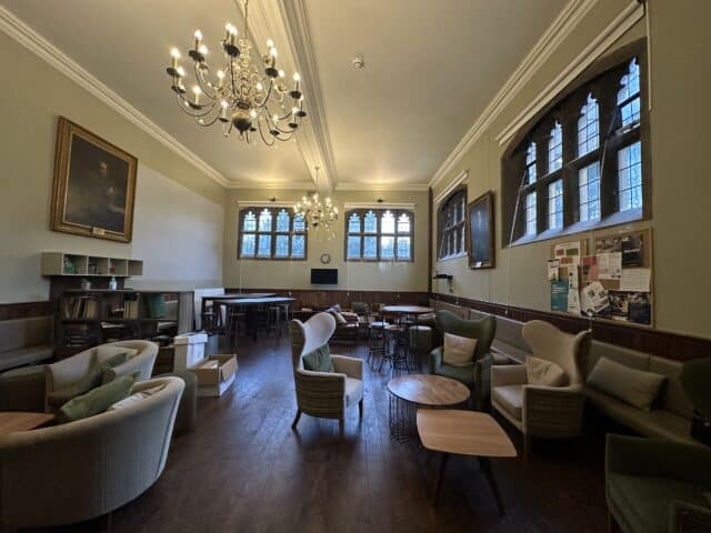 A room with arched windows, chandeliers, chairs and sofas, coffee tables and shelves.