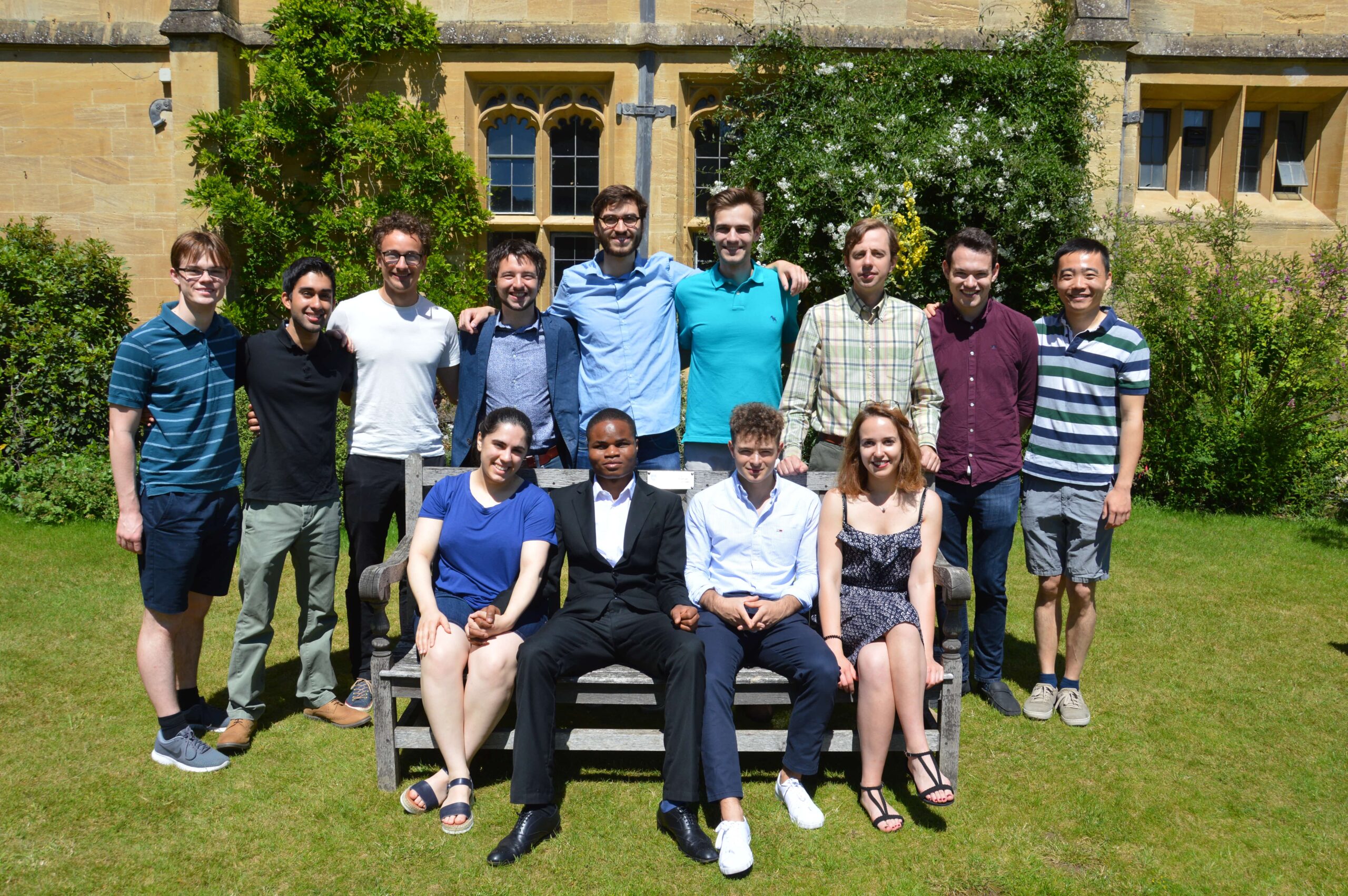 group of students sat on bench and some standing behind