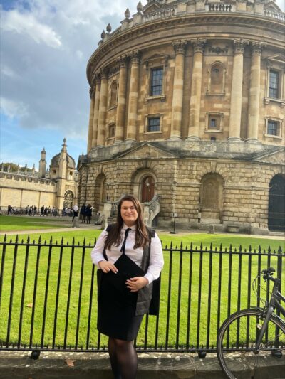 Amelia Oxlade in academic gown by the Radcliffe Camera